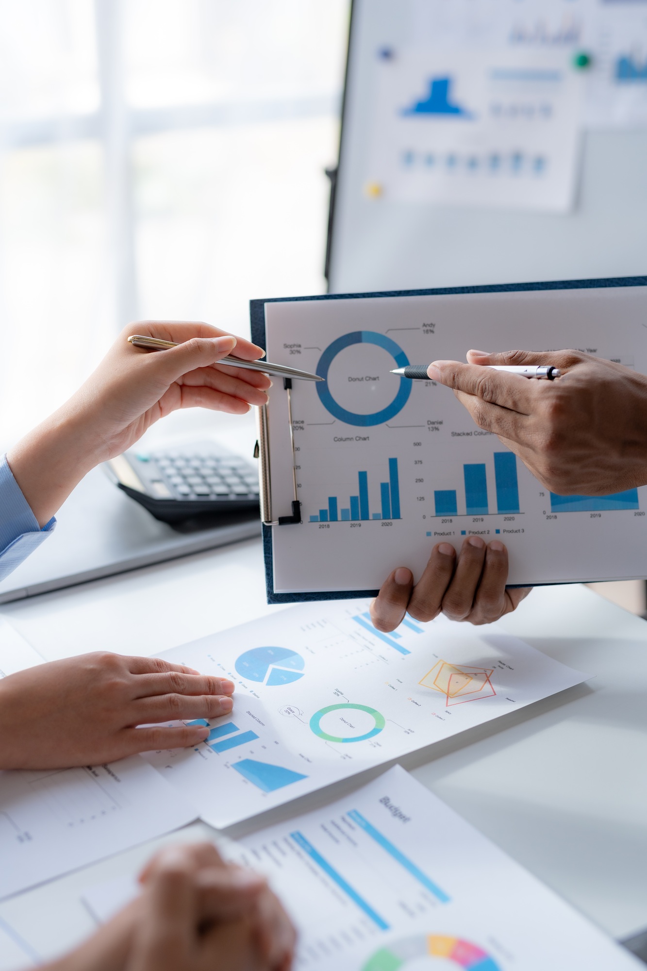 Business team together making investment plan at meeting pointing at graph and chart.